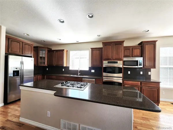 a kitchen with stainless steel appliances granite countertop a refrigerator stove microwave and sink