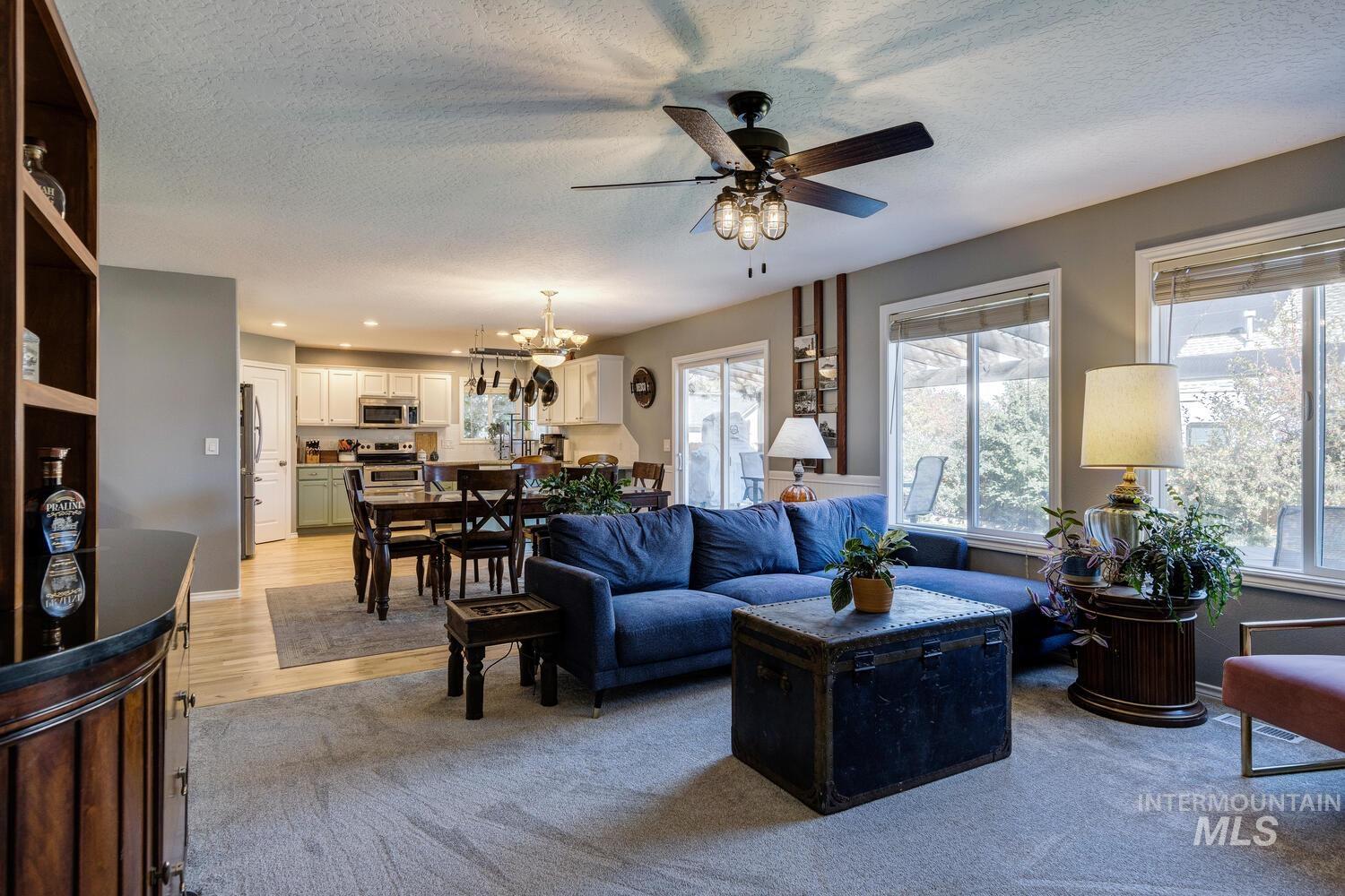 4428 West Campfire Street Meridian, ID 83646 - Photo 12 of 46 Living area with a textured ceiling, a chandelier, light wood-type flooring, and a ceiling fan