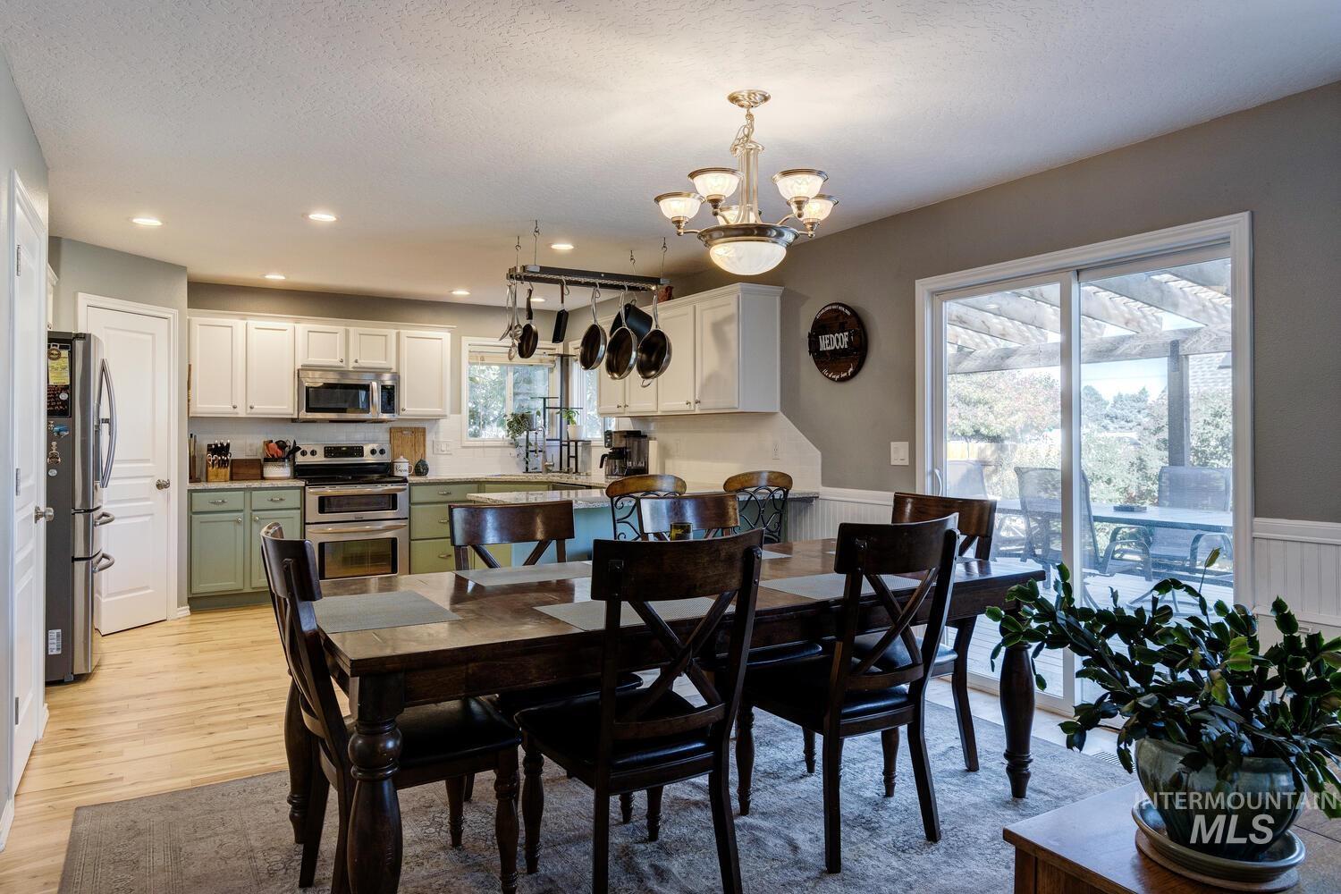 4428 West Campfire Street Meridian, ID 83646 - Photo 13 of 46 Dining area featuring a chandelier, light wood-type flooring, a wainscoted wall, recessed lighting, and a textured ceiling
