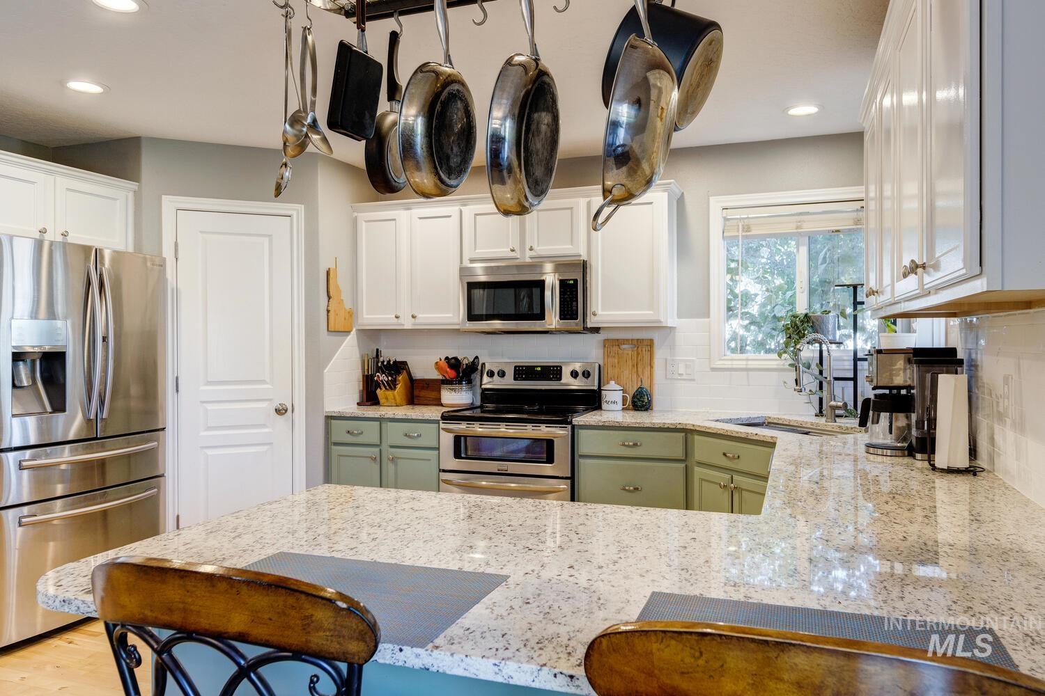 4428 West Campfire Street Meridian, ID 83646 - Photo 15 of 46 Kitchen featuring light stone counters, appliances with stainless steel finishes, white cabinets, recessed lighting, and backsplash