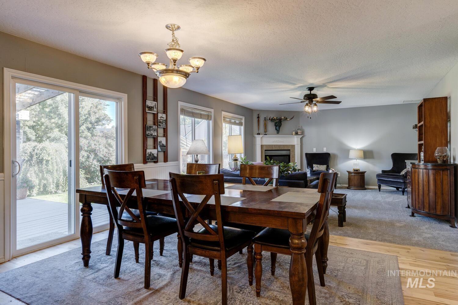 4428 West Campfire Street Meridian, ID 83646 - Photo 18 of 46 Dining area with light wood-type flooring, a tile fireplace, a textured ceiling, a chandelier, and ceiling fan