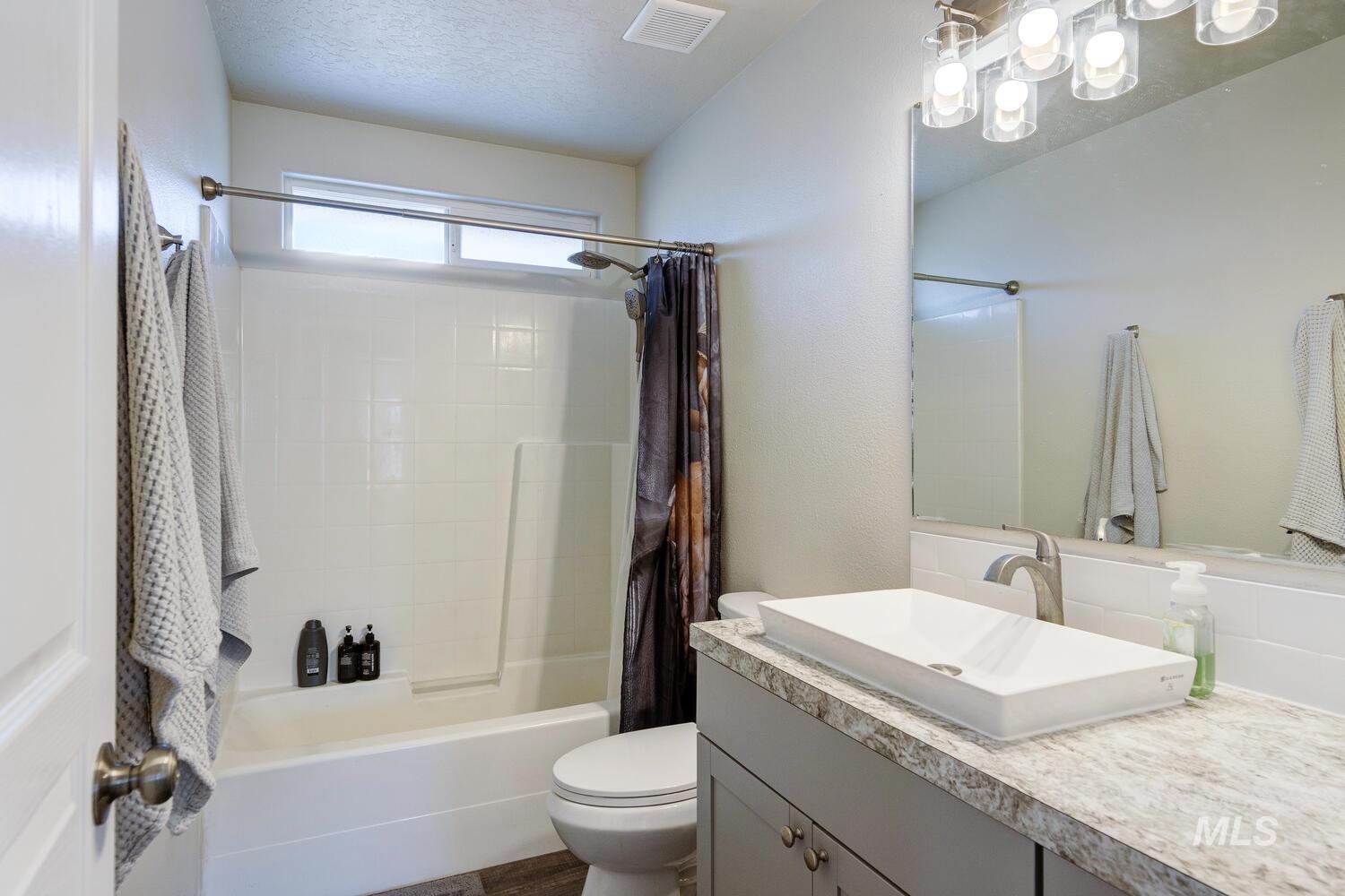 4428 West Campfire Street Meridian, ID 83646 - Photo 35 of 46 Bathroom featuring shower / bath combo with shower curtain, vanity, and a textured ceiling