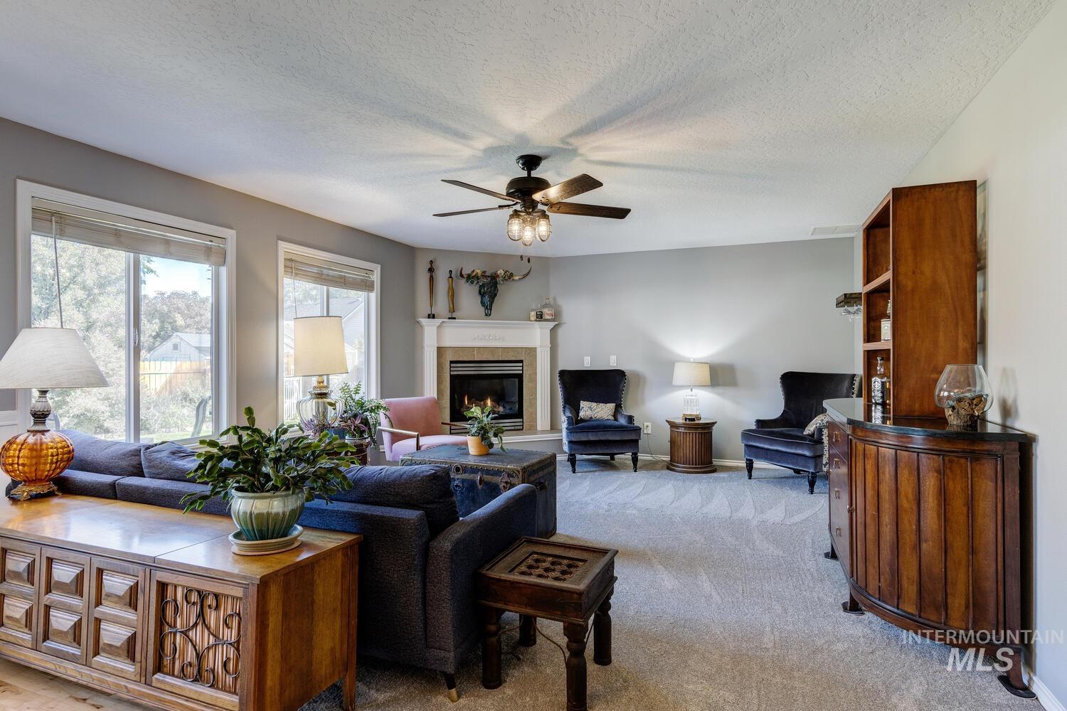 4428 West Campfire Street Meridian, ID 83646 - Photo 8 of 46 Living room with a textured ceiling, a tiled fireplace, light colored carpet, and ceiling fan