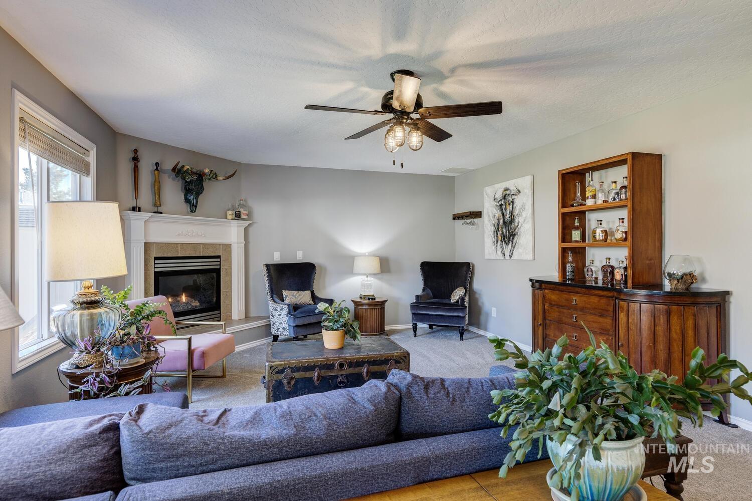 4428 West Campfire Street Meridian, ID 83646 - Photo 9 of 46 Living area featuring a tiled fireplace, carpet flooring, and ceiling fan