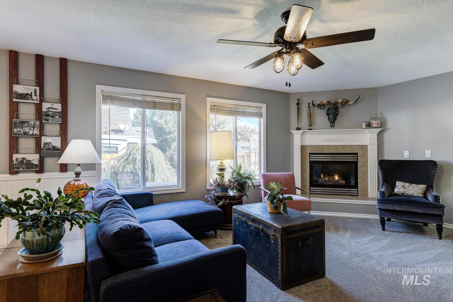 4428 West Campfire Street Meridian, ID 83646 - Photo 10 of 46 Living room with a tile fireplace, carpet flooring, a textured ceiling, and ceiling fan