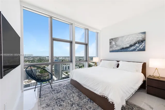 a bedroom with a bed a chair and next to a window
