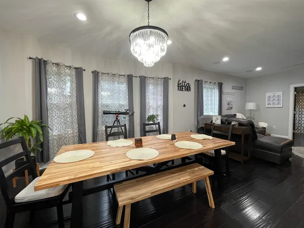 a dining room with wooden floor a chandelier a wooden table and chairs