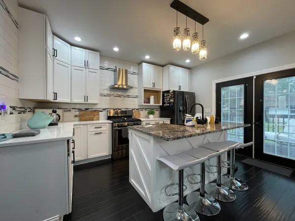 a kitchen with granite countertop a stove top oven a sink dishwasher a dining table and chairs with wooden floor