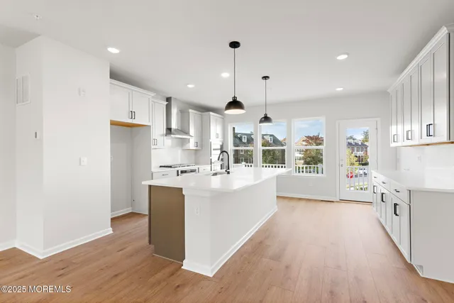 a large kitchen with stainless steel appliances kitchen island a large counter top and a wooden floors
