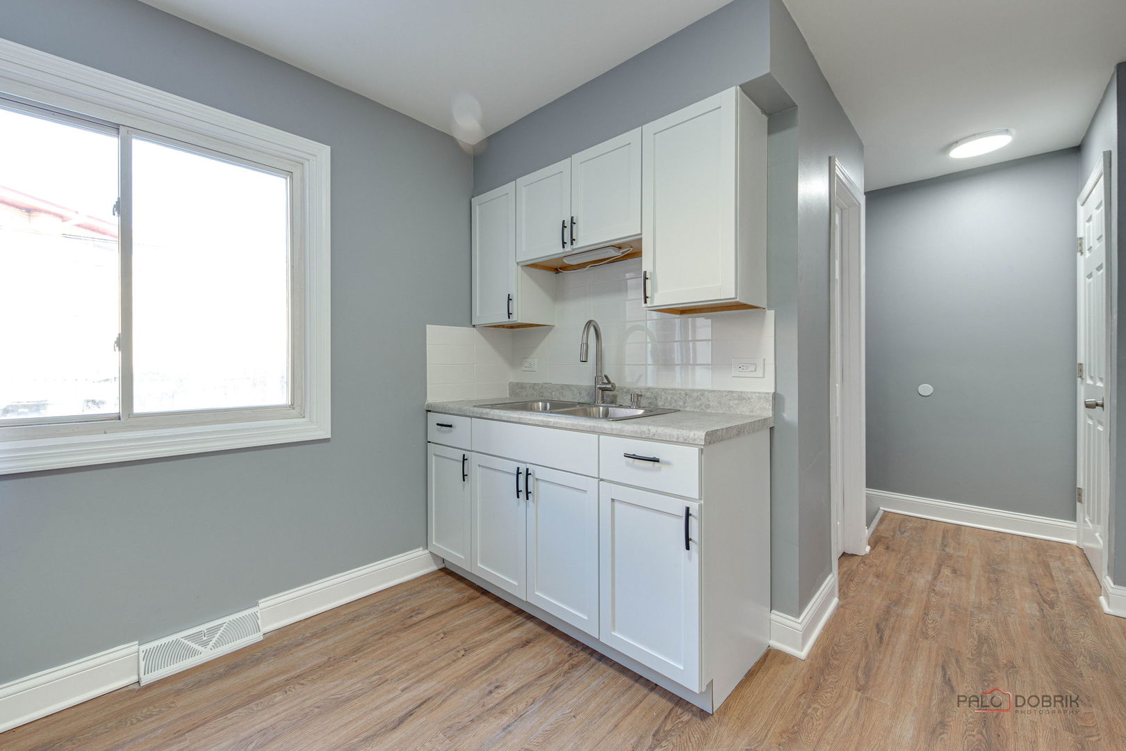 9463 Niles Center Road, Unit E Skokie, IL 60076 - Photo 11 of 30 a kitchen with kitchen island white cabinets and wooden floor