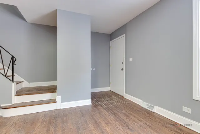 a view of an empty room with wooden floor and entryway
