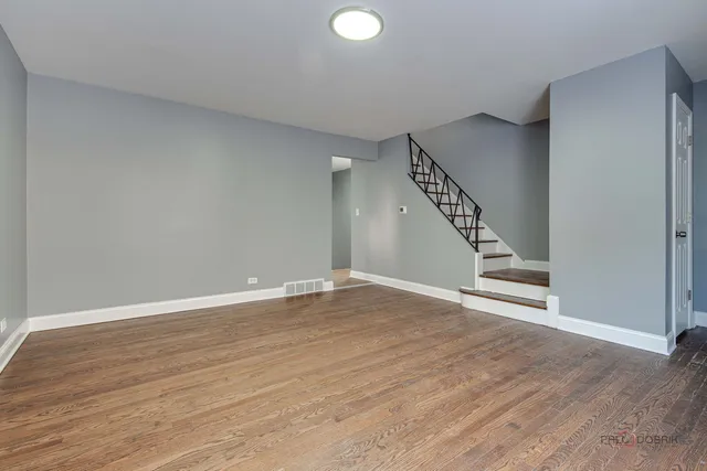 a view of an empty room with wooden floor and stairs