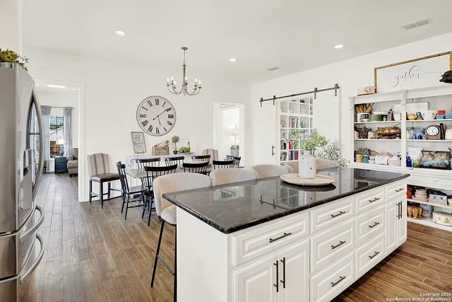 a kitchen with granite countertop a stove a sink a dining table and chairs with wooden floor