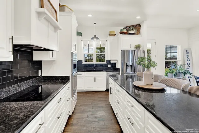 a large kitchen with granite countertop a sink stainless steel appliances and a counter space