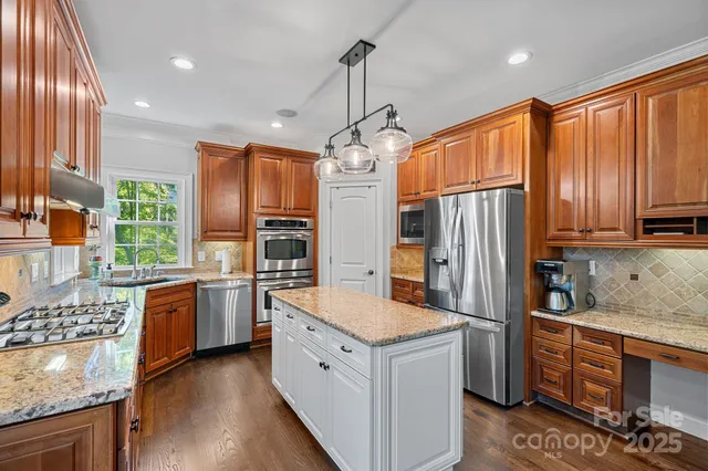 a kitchen with stainless steel appliances granite countertop a refrigerator a stove top oven a sink and dishwasher
