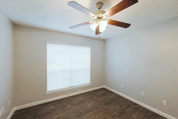 an empty room with a window and a fan