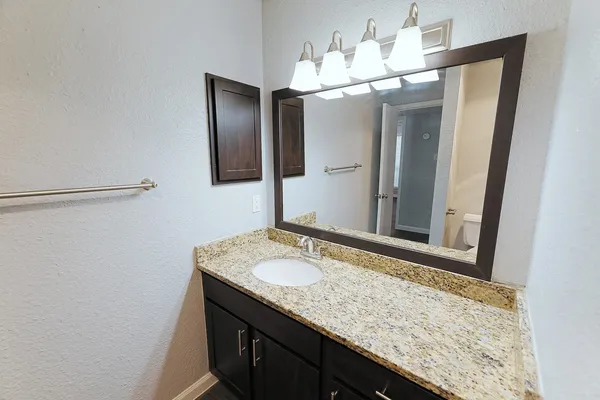 a bathroom with a granite countertop sink and a mirror