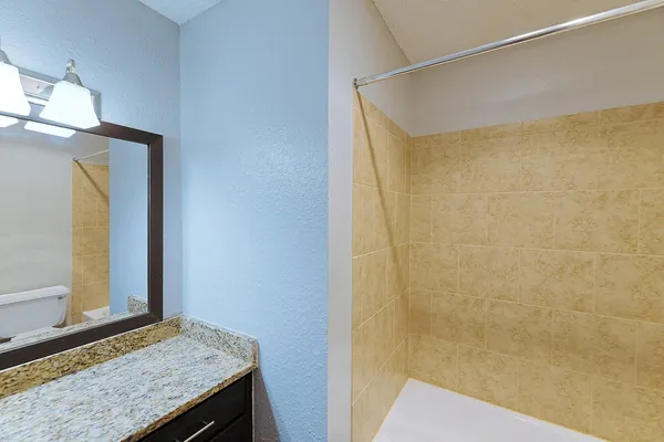 a bathroom with a granite countertop sink and a mirror