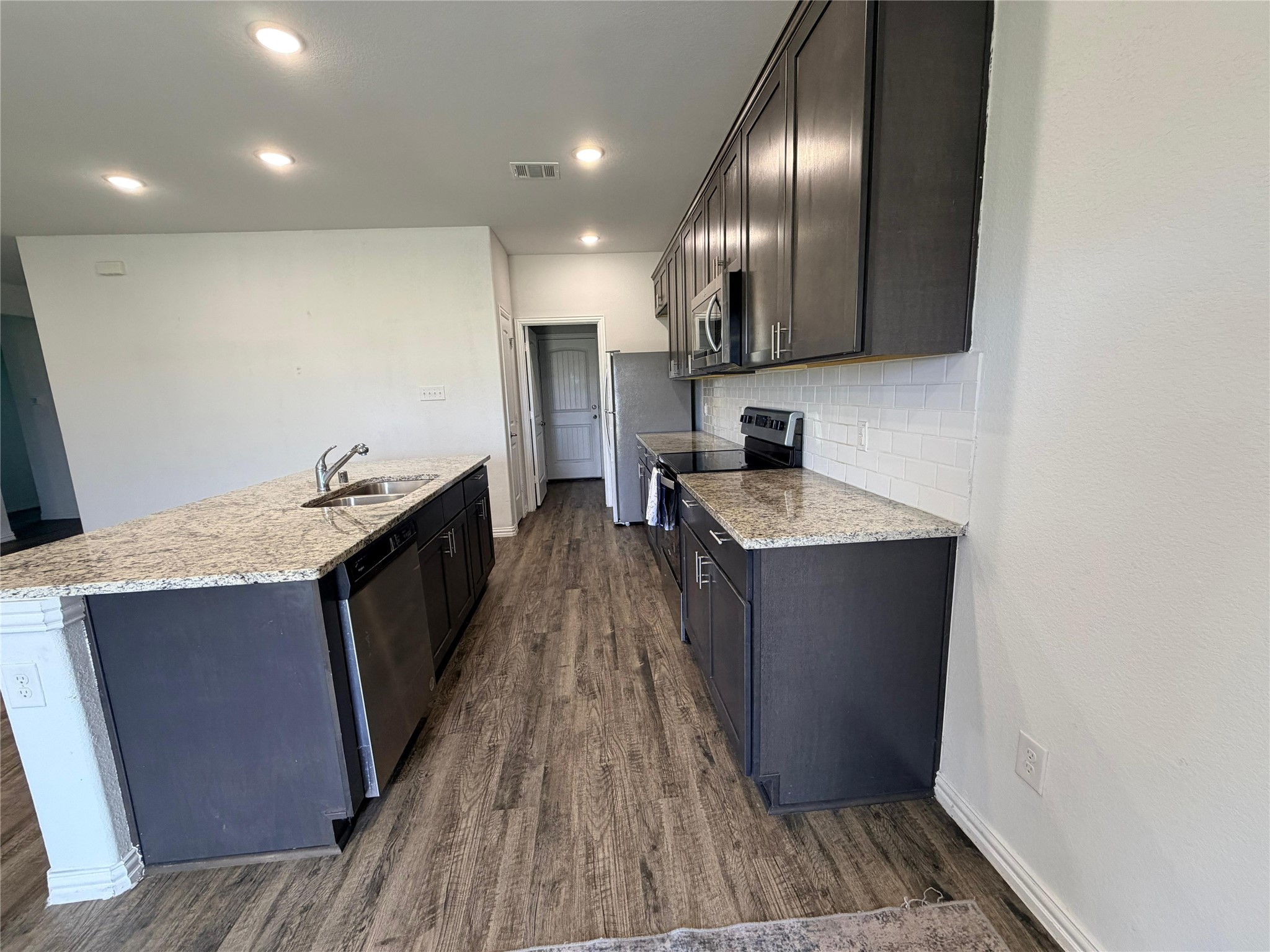 870 5102nd Road Cleveland, TX 77327 - Photo 6 of 27 a kitchen with granite countertop a sink stove and refrigerator