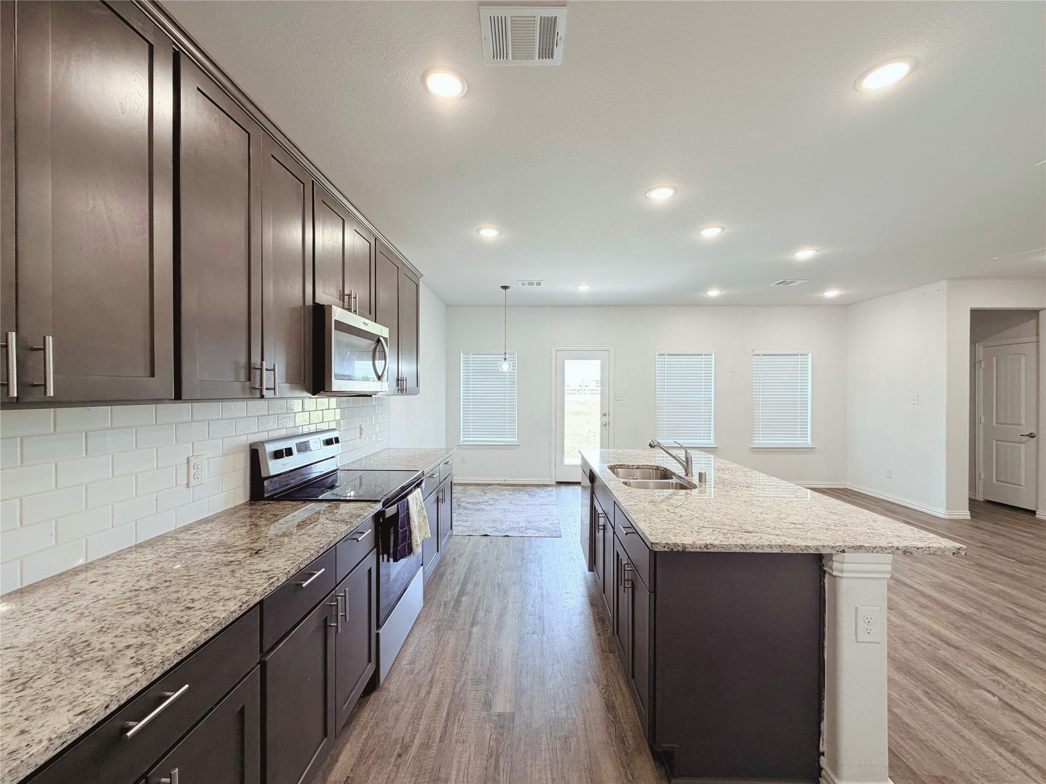 870 5102nd Road Cleveland, TX 77327 - Photo 7 of 27 a large kitchen with stainless steel appliances granite countertop plenty wooden cabinets counter space a sink and wooden floor