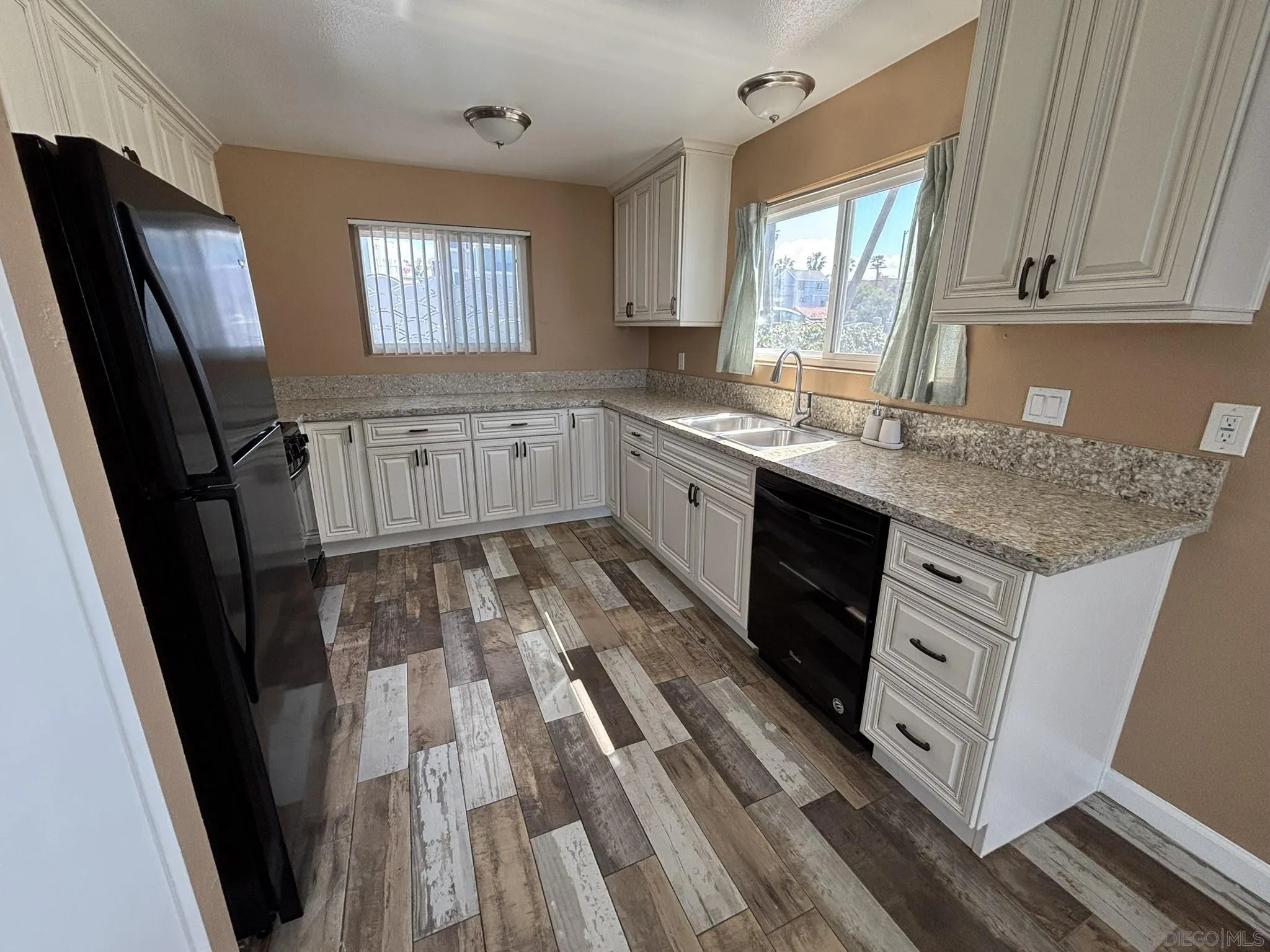 514 South The Strand, Unit D Oceanside, CA 92054 - Photo 10 of 18 a kitchen with white cabinets sink and window
