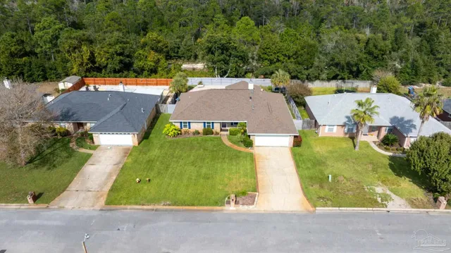an aerial view of a house with swimming pool and large trees