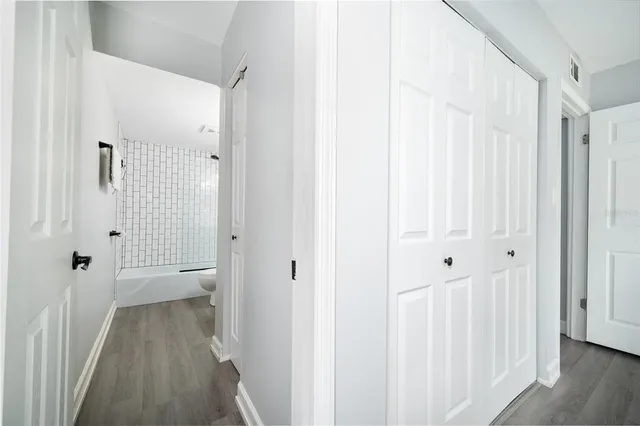 a view of a hallway with wooden floor and closet area