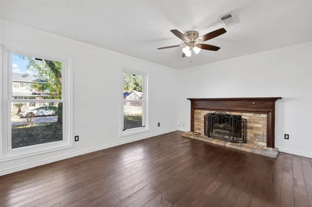 a view of an empty room with window and wooden floor