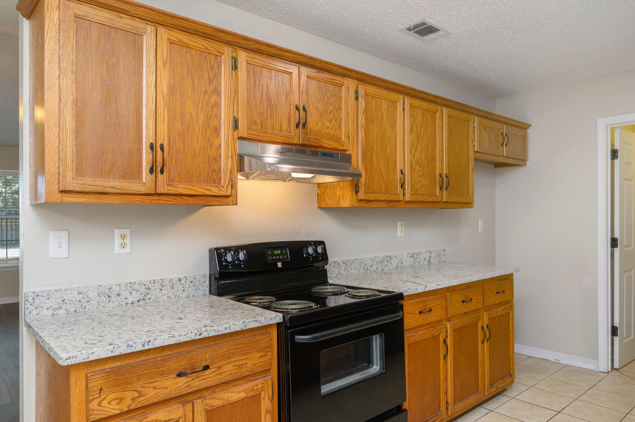 502 Hyde Park Drive Crestview, FL 32539 - Photo 11 of 35 a kitchen with stainless steel appliances granite countertop white cabinets and a stove top oven