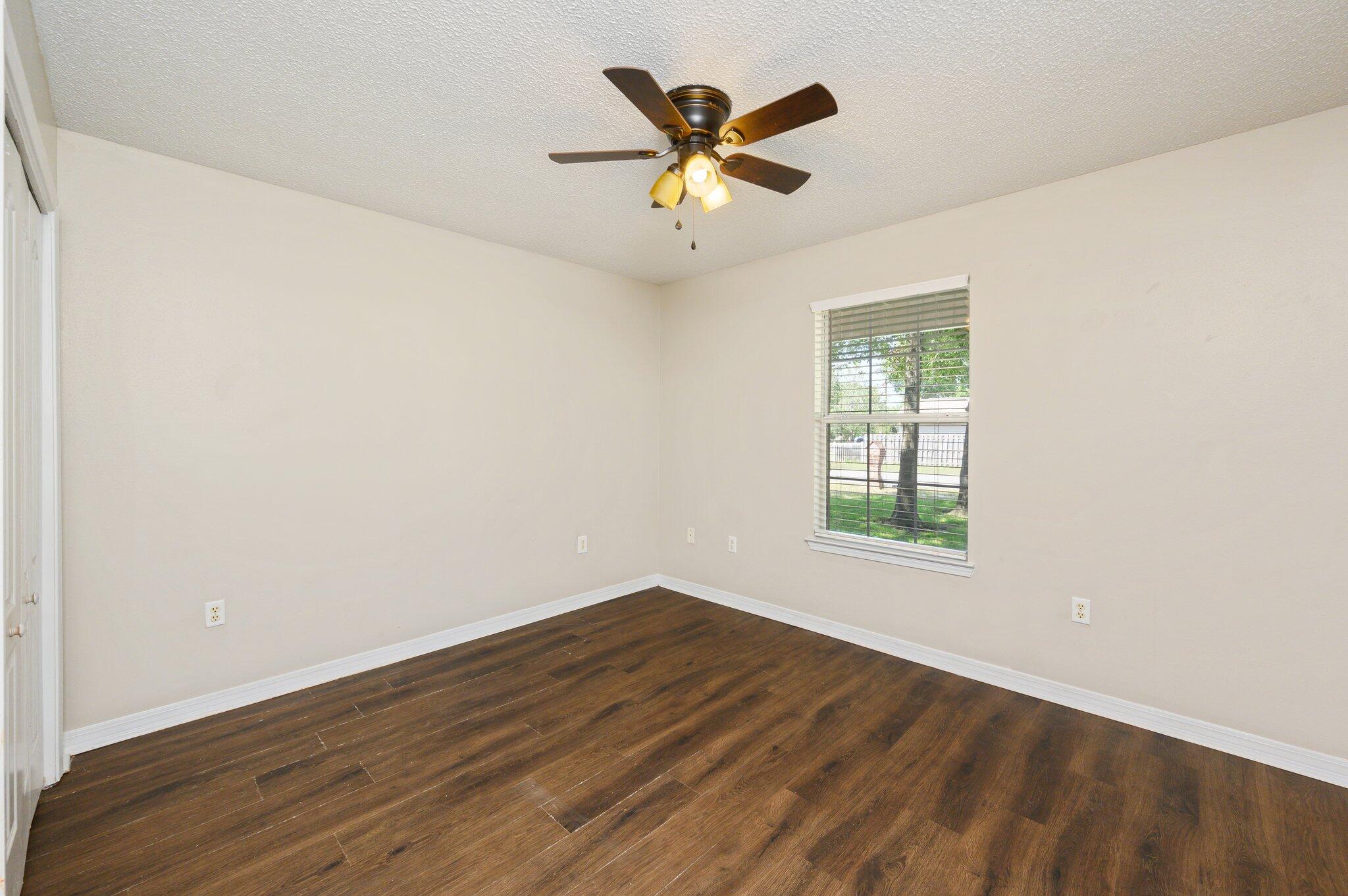 502 Hyde Park Drive Crestview, FL 32539 - Photo 16 of 35 an empty room with wooden floor and ceiling fan