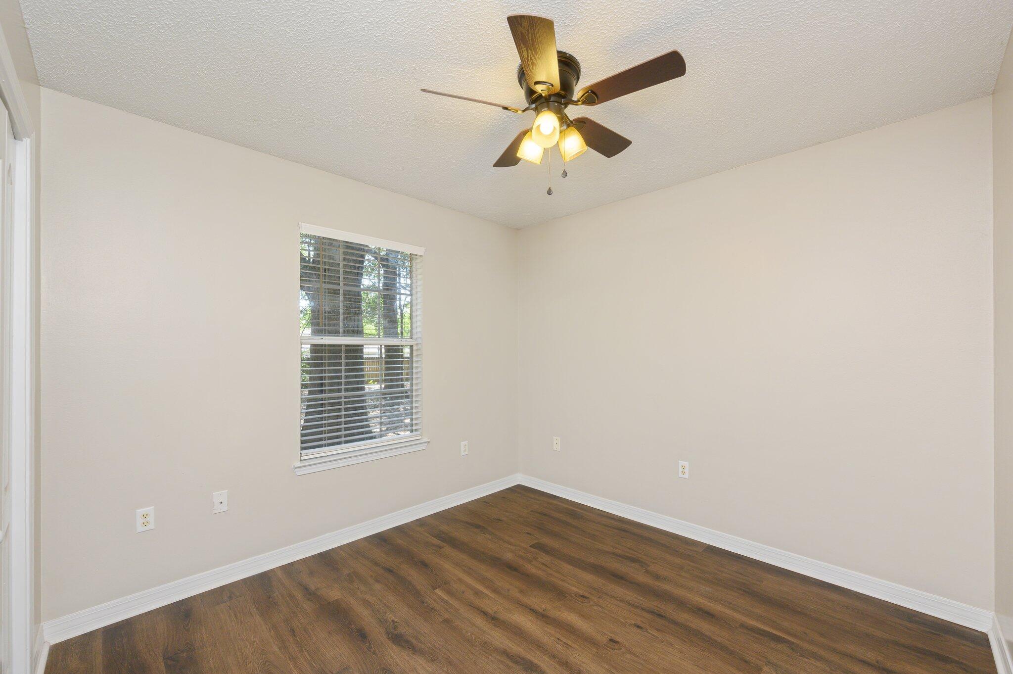 502 Hyde Park Drive Crestview, FL 32539 - Photo 18 of 35 an empty room with wooden floor fan and windows