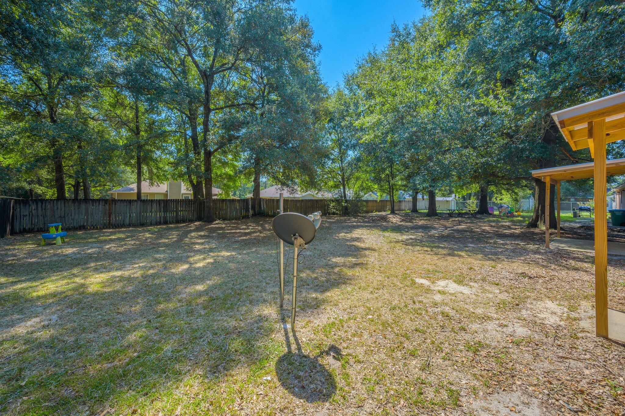 502 Hyde Park Drive Crestview, FL 32539 - Photo 32 of 35 a backyard of a house with lots of plants and large tree