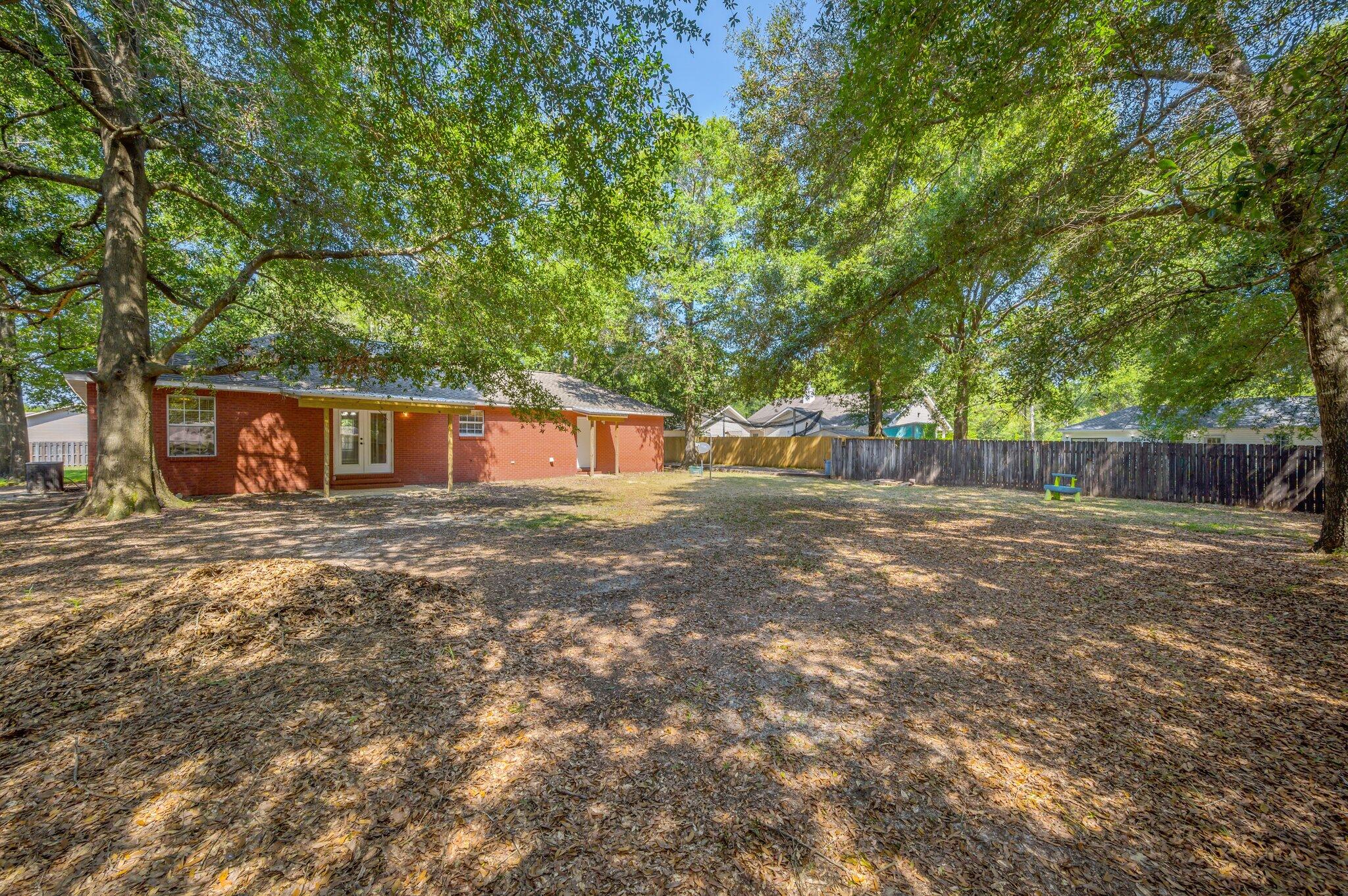502 Hyde Park Drive Crestview, FL 32539 - Photo 34 of 35 a backyard of a house with large trees and wooden fence