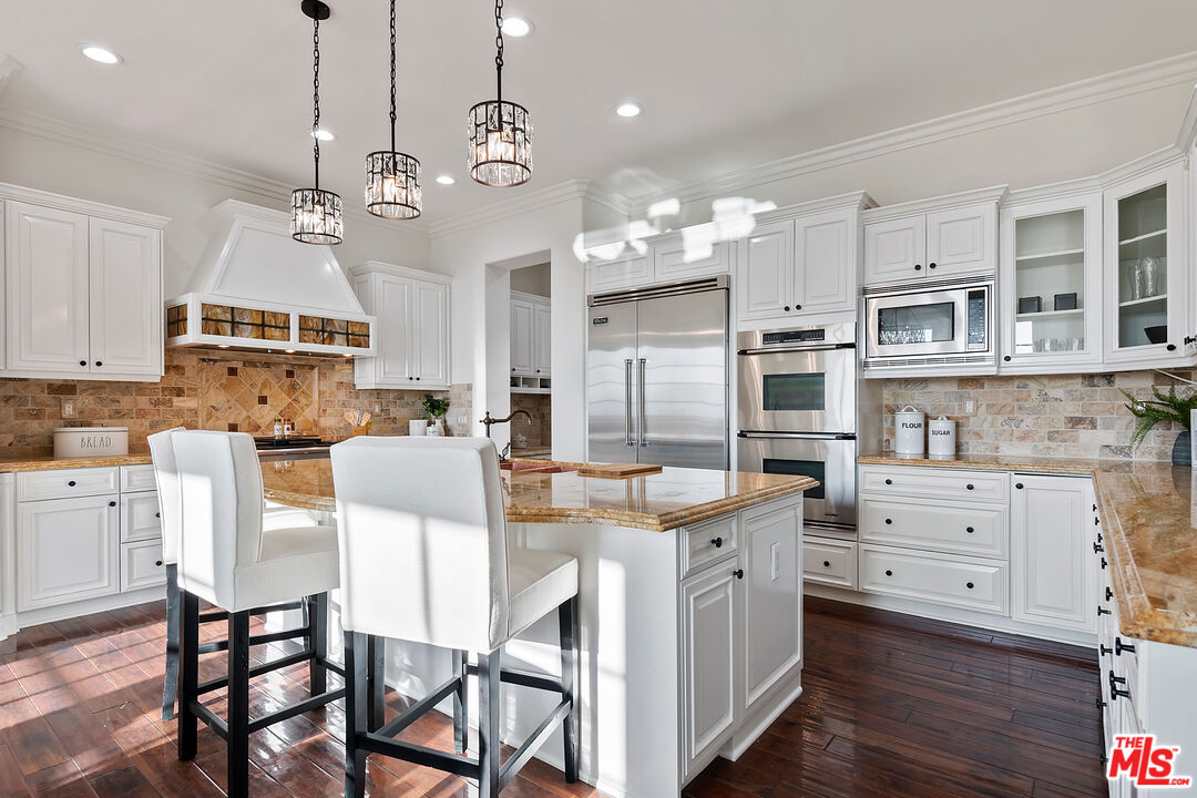 25430 Prado De Azul Calabasas, CA 91302 - Photo 7 of 51 a kitchen with stainless steel appliances kitchen island granite countertop a table chairs and cabinets