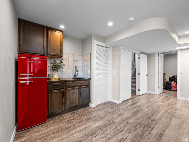 7 Sterling Loop Vineyard, UT 84059 - Photo 32 of 43 Wet bar area featuring a retro-style red refrigerator, wood cabinetry, stone-look countertop, and a tiled backsplash