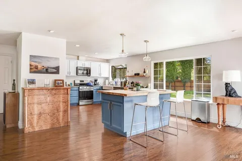 a kitchen with stainless steel appliances granite countertop a refrigerator a stove top oven and a view of living room