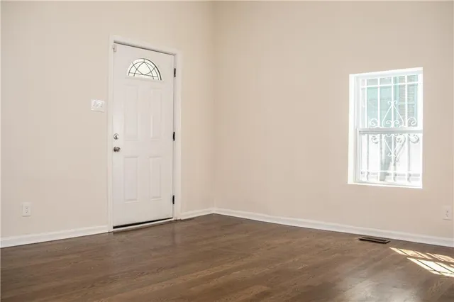 an empty room with wooden floor and windows