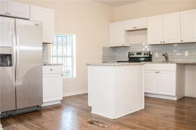 a kitchen with a refrigerator a stove a sink and white cabinets with wooden floor