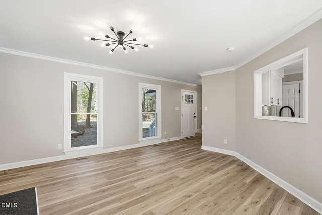a view of an empty room with a window and a kitchen