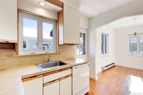 a kitchen with stainless steel appliances granite countertop a sink and a white cabinets with wooden floor