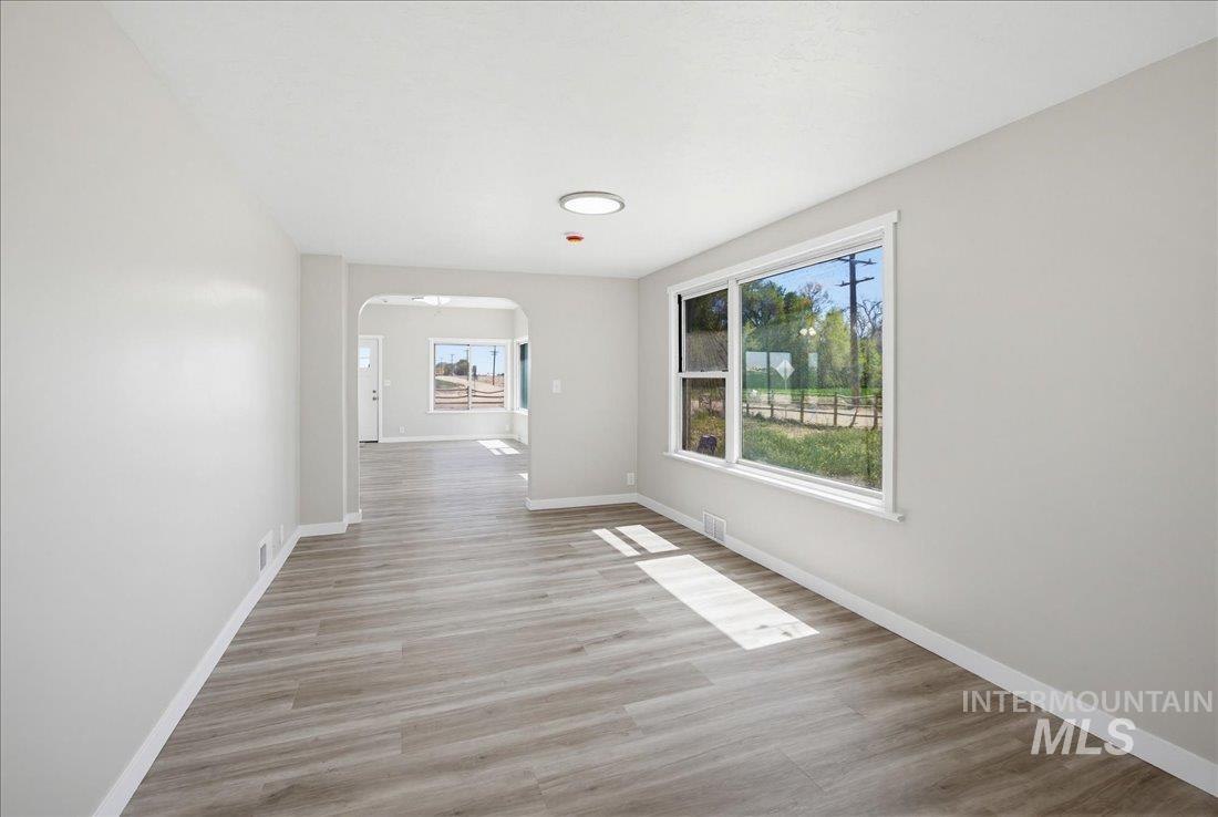 30013 Apple Valley Road Parma, ID 83660 - Photo 19 of 25 Spacious living area featuring light gray walls, wood-finish flooring, a large window, and an arched doorway