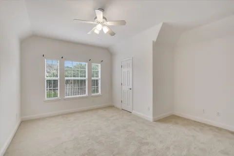 an empty room with chandelier fan and windows