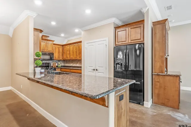 a kitchen with stainless steel appliances granite countertop a sink and a refrigerator