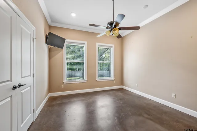 an empty room with wooden floor fan and windows