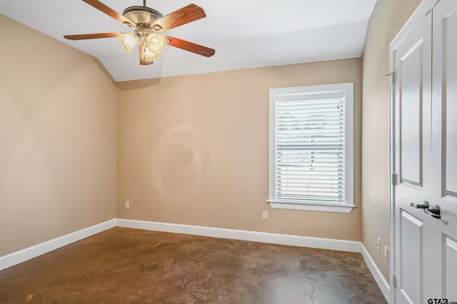 an empty room with windows and fan
