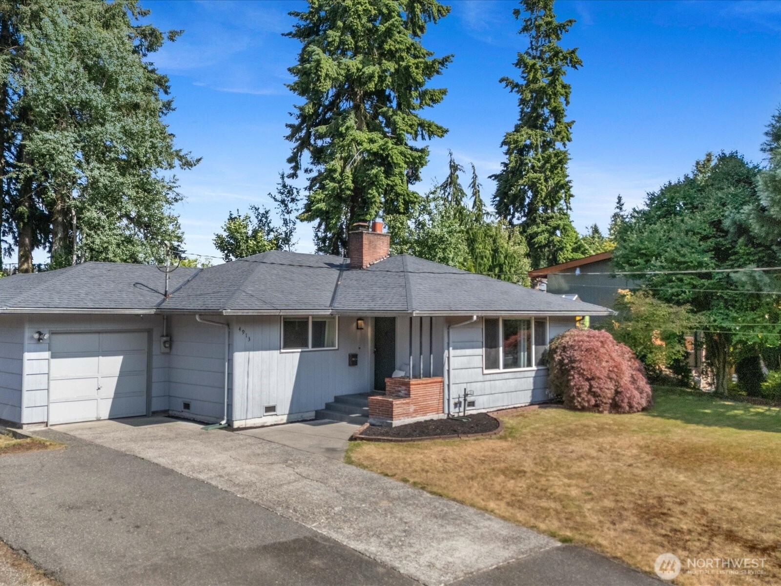 a front view of a house with a garden and trees