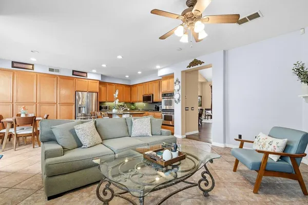 a living room with furniture kitchen view and a chandelier
