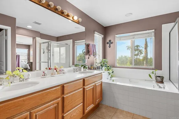 a bathroom with a bathtub a double vanity sink and mirror