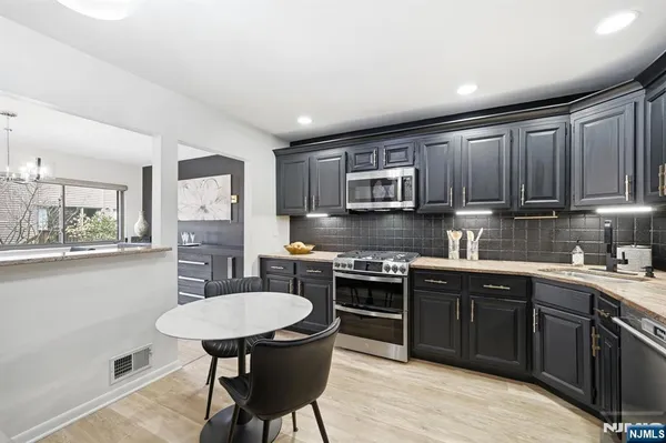 a kitchen with stainless steel appliances granite countertop a sink a stove top oven a counter space and cabinets