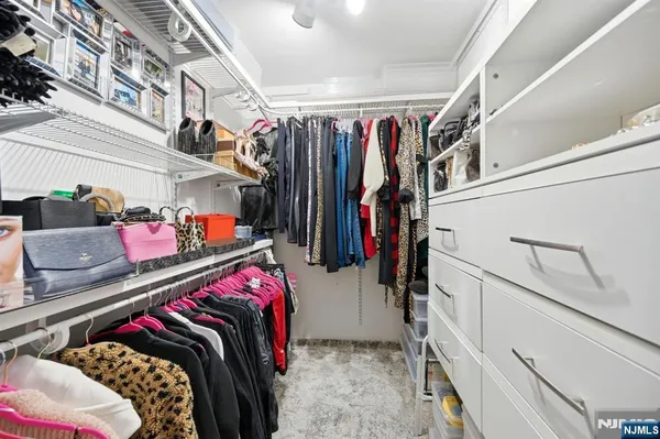 a view of walk in closet with clothes and shoes
